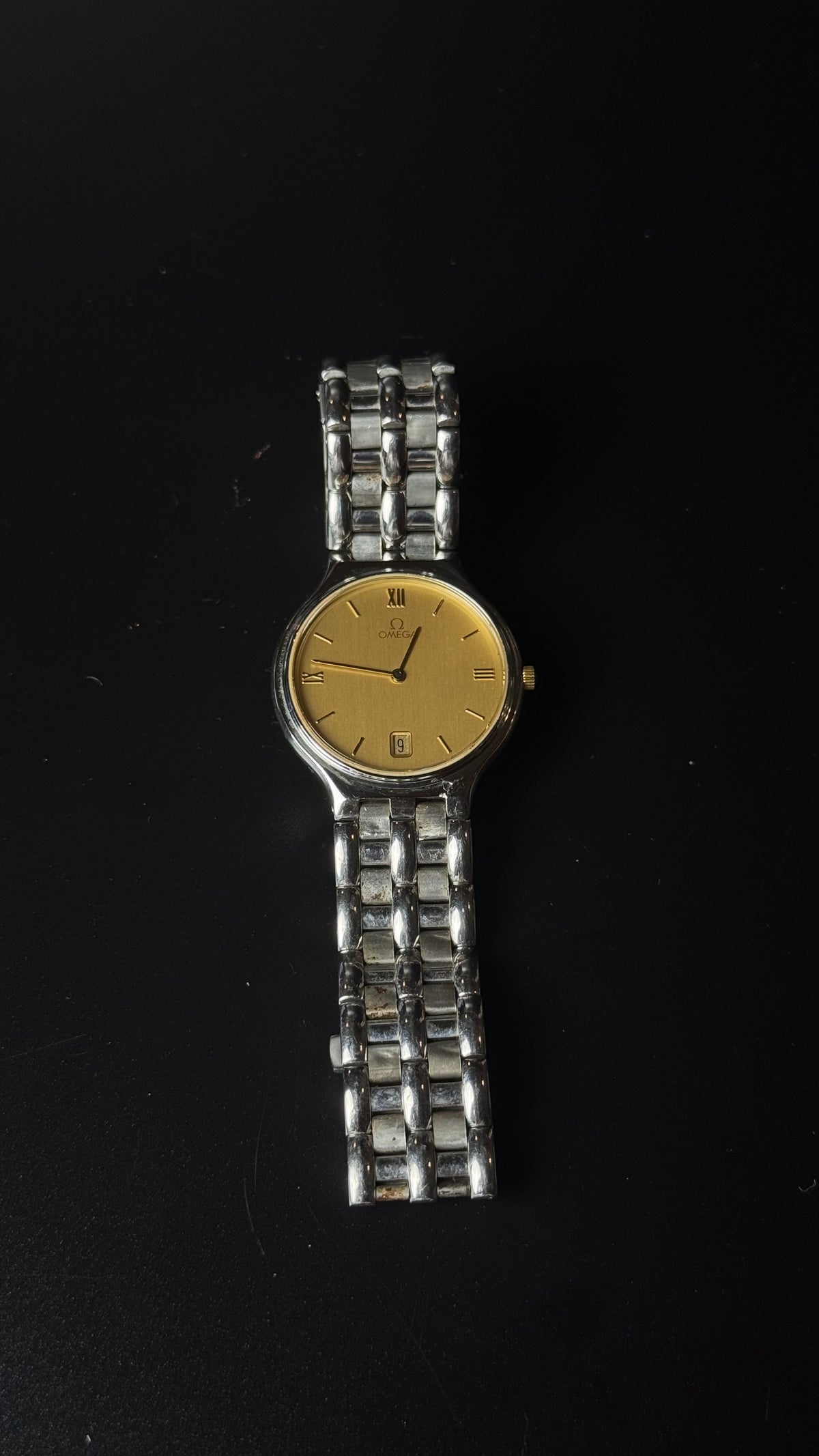 Omega – złota tarcza, cyfry rzymskie, datownik, srebrna bransoleta
