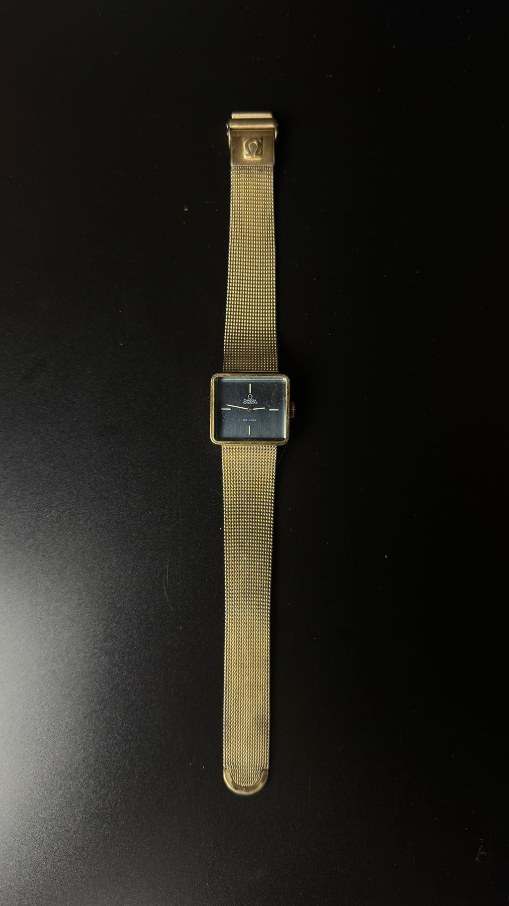 Omega De Ville Automatic – kwadratowa koperta, grafitowa tarcza, złota bransoleta mesh