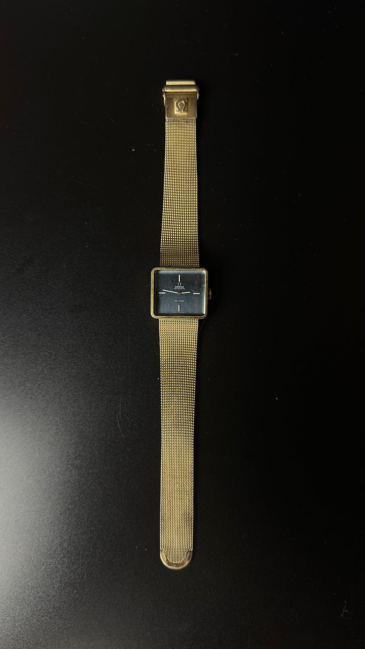 Omega De Ville Automatic – kwadratowa koperta, grafitowa tarcza, złota bransoleta mesh