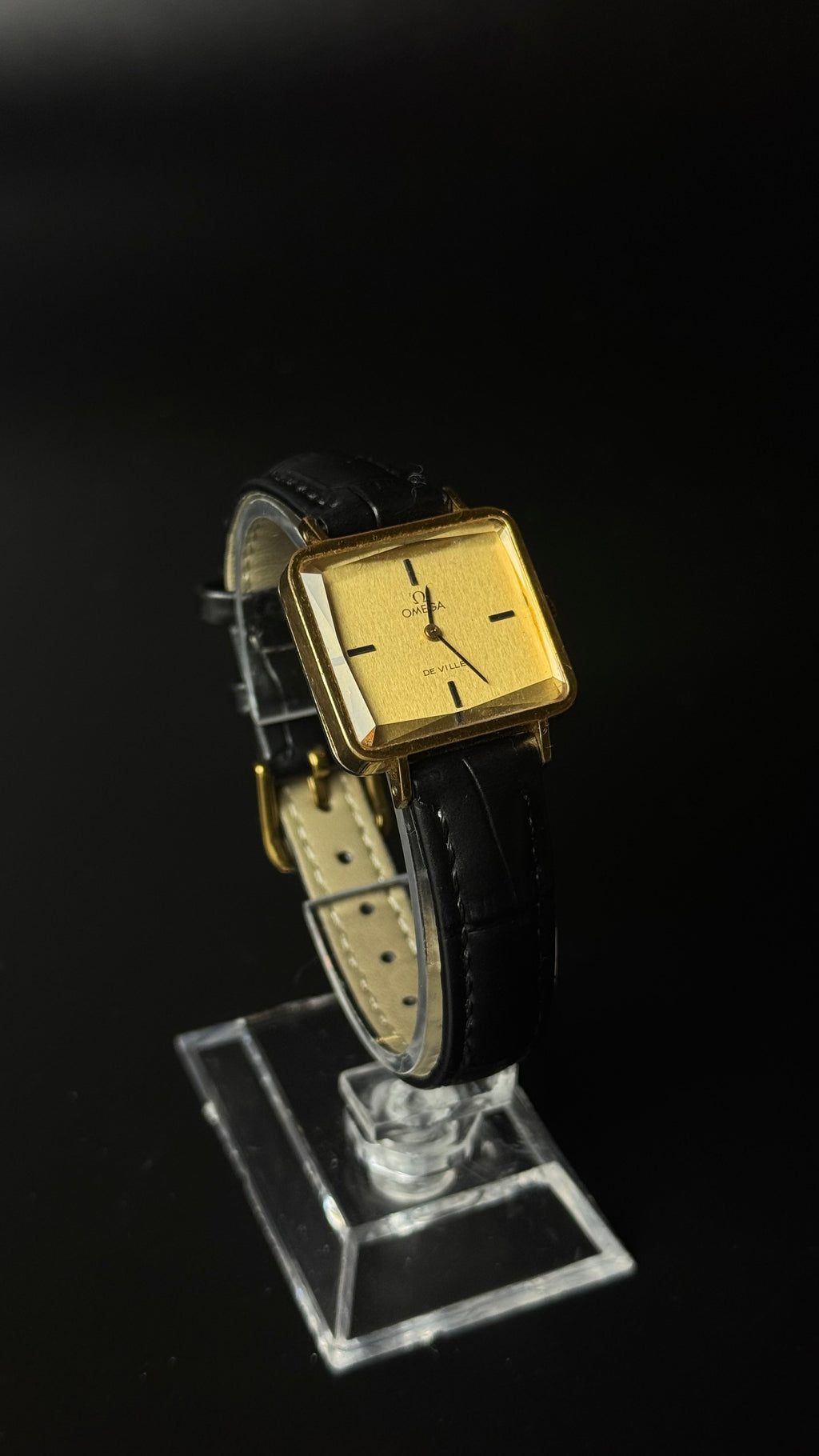 Omega De Ville – kwadratowa koperta, złota tarcza, czarny pasek